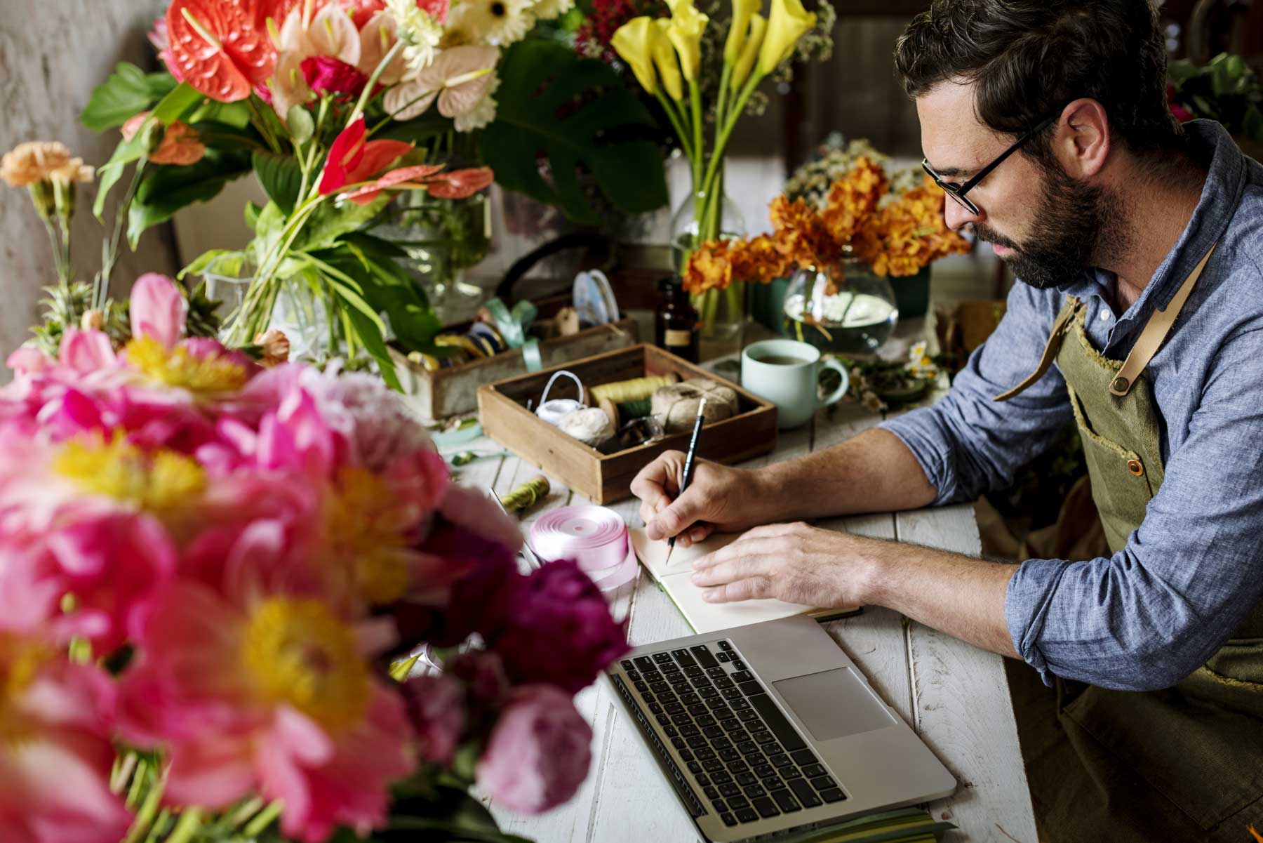 Man works on his e-commerce business in flower shop