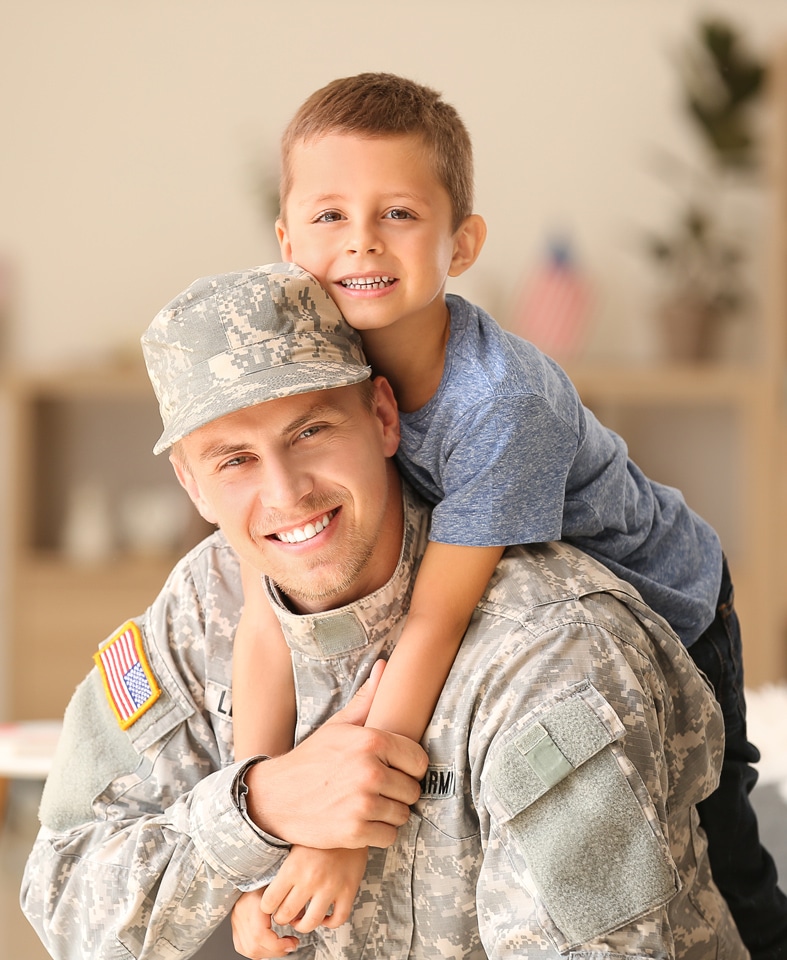 Man wearing U.S. military uniform with son on back