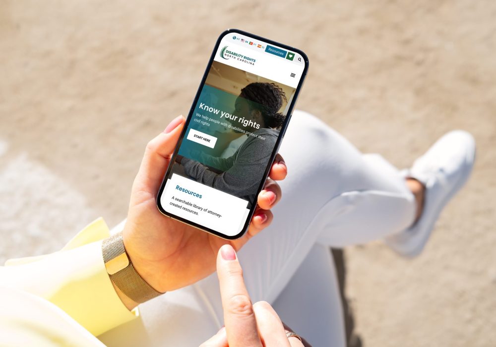 Woman outside looking at Disability Rights North Carolina on her phone